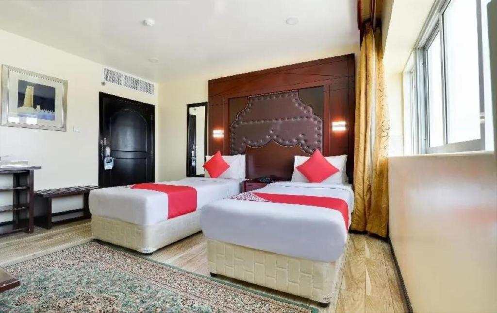 富查伊拉SHH Hotel的两张位于酒店客房的床铺,配有红色枕头