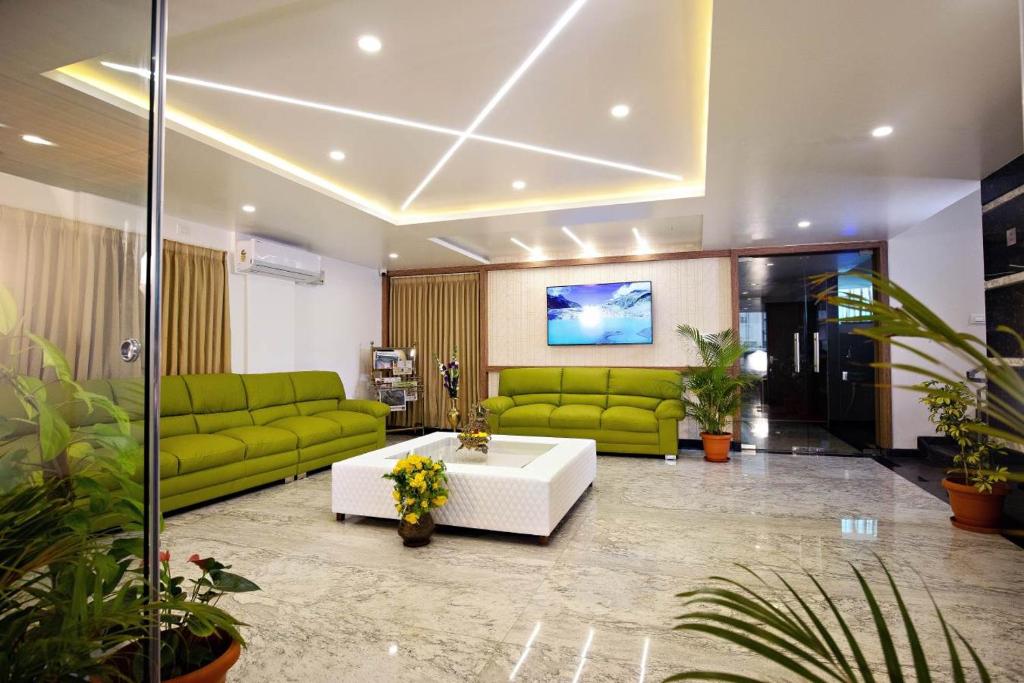 耶拉汉卡Hotel Grand Villa的客厅配有绿色沙发和白色桌子