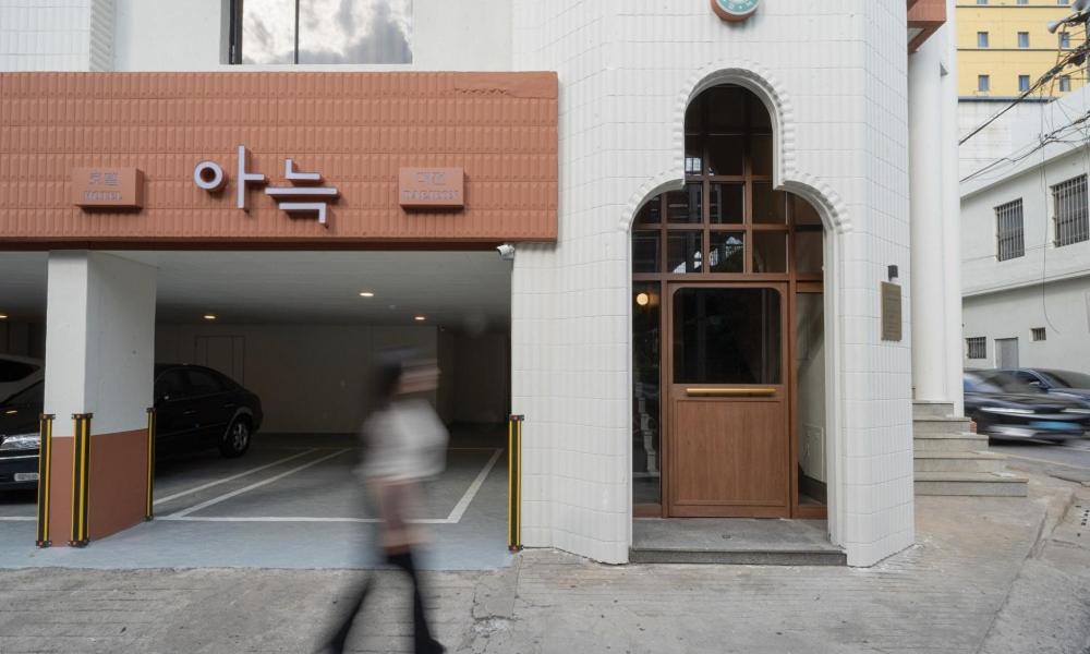 大田Annk Hotel Daejeon Daeheung的手持旋转门走过建筑物的人