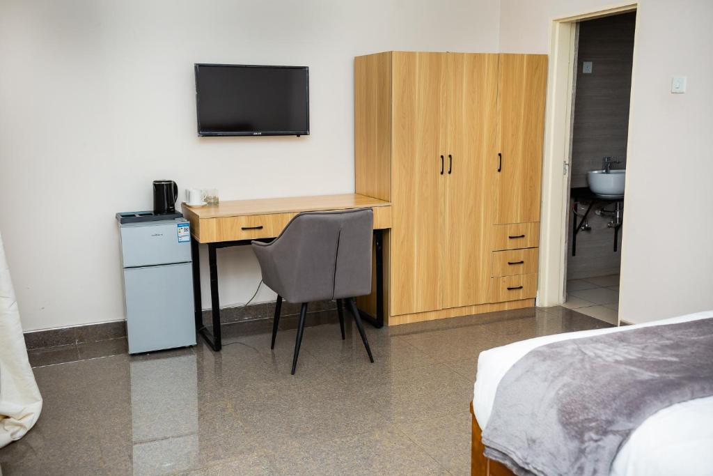 卢萨卡Eleganciana Lodges Limited的客房设有书桌、床和电视。
