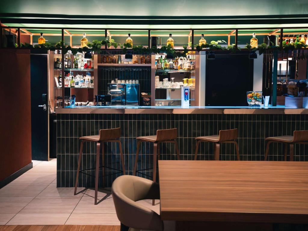 里尔诺沃特里尔中央格兰德广场酒店的餐厅设有带凳子的酒吧