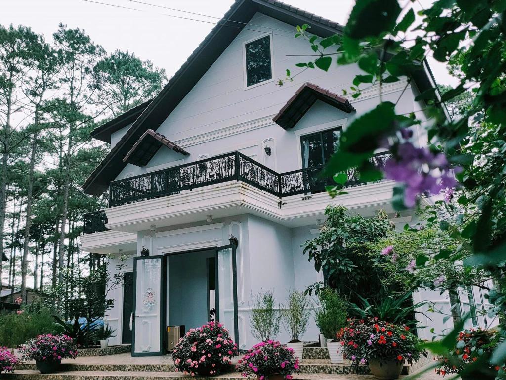Kon PlongKhách Sạn Măng Đen Xanh的带阳台和鲜花的白色房屋
