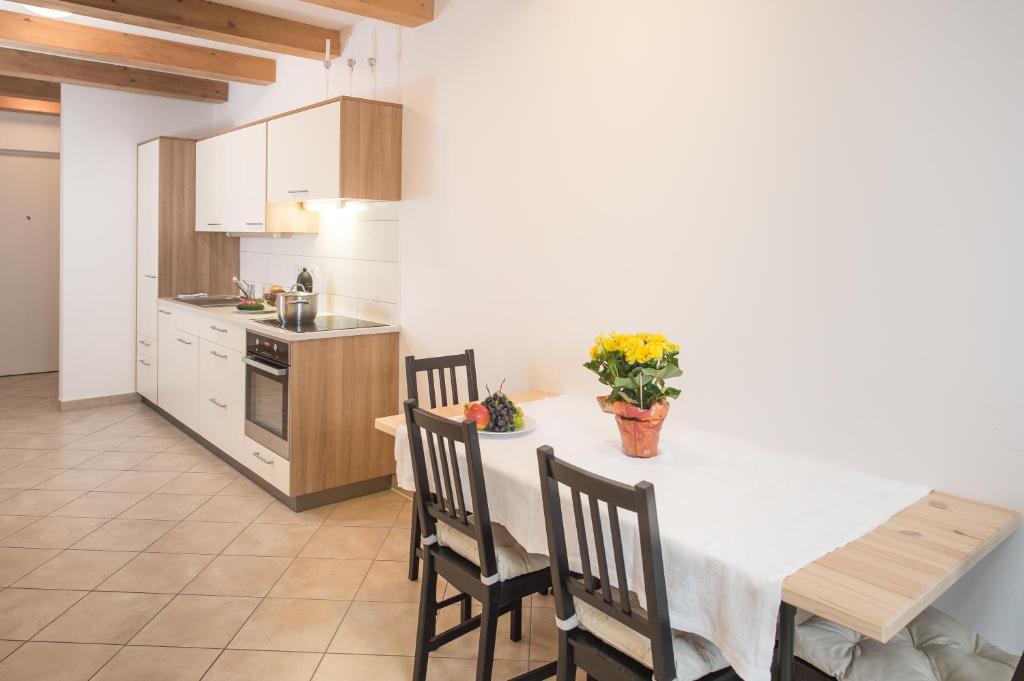 博尔扎诺温特勒公寓的一间带白色桌椅的厨房和一间带吧台的厨房
