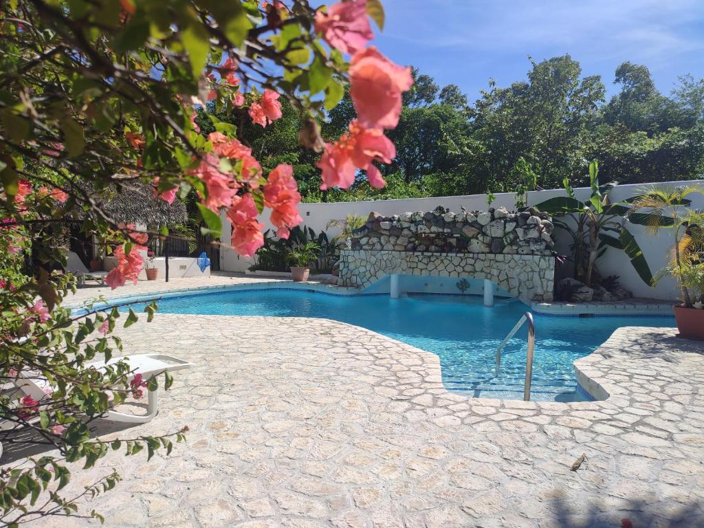 尼格瑞尔Ltu Garden的一座游泳池,位于一个拥有粉红色花卉的庭院内