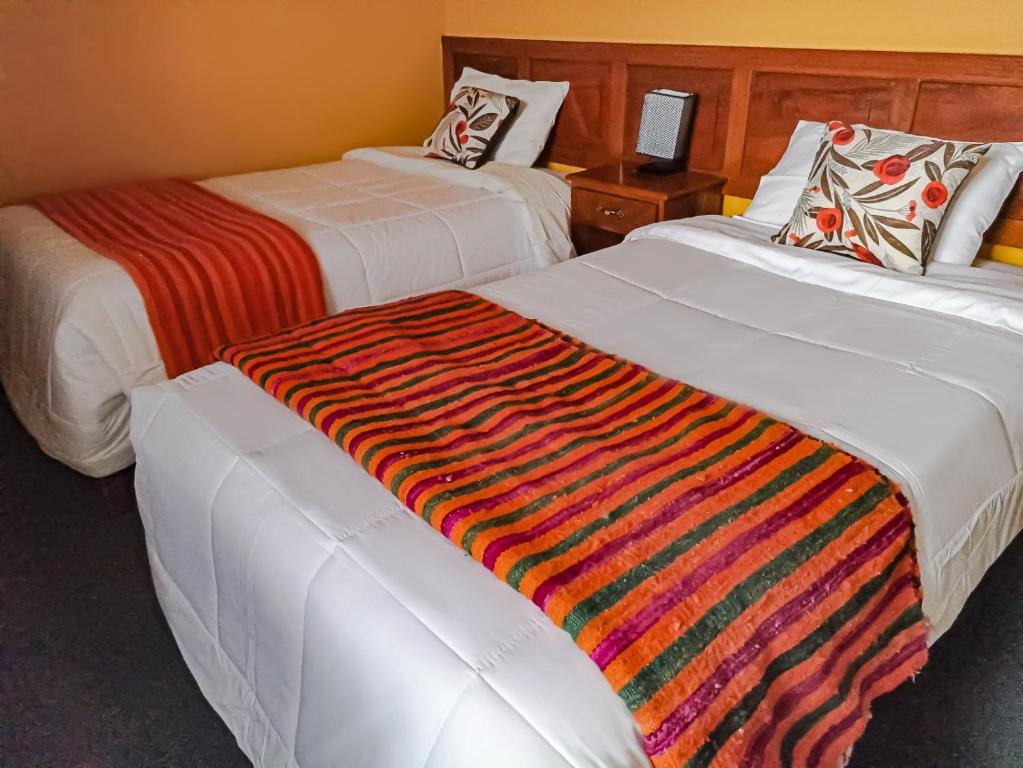 瓦拉斯Huaraz Center Hostal的两张位于酒店客房的床,上面有彩色毯子