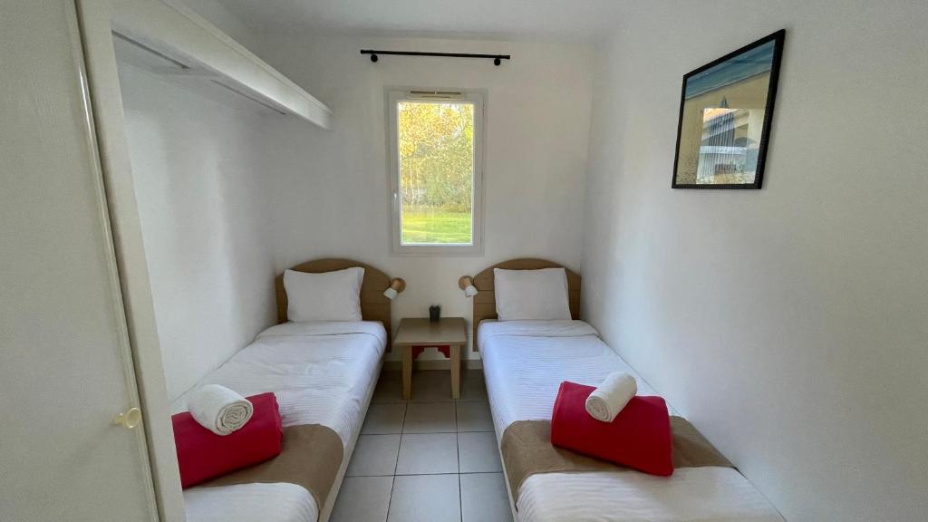 翁德尔Chalet paisible à la plage, piscine et tennis的小房间设有两张带红色枕头的床