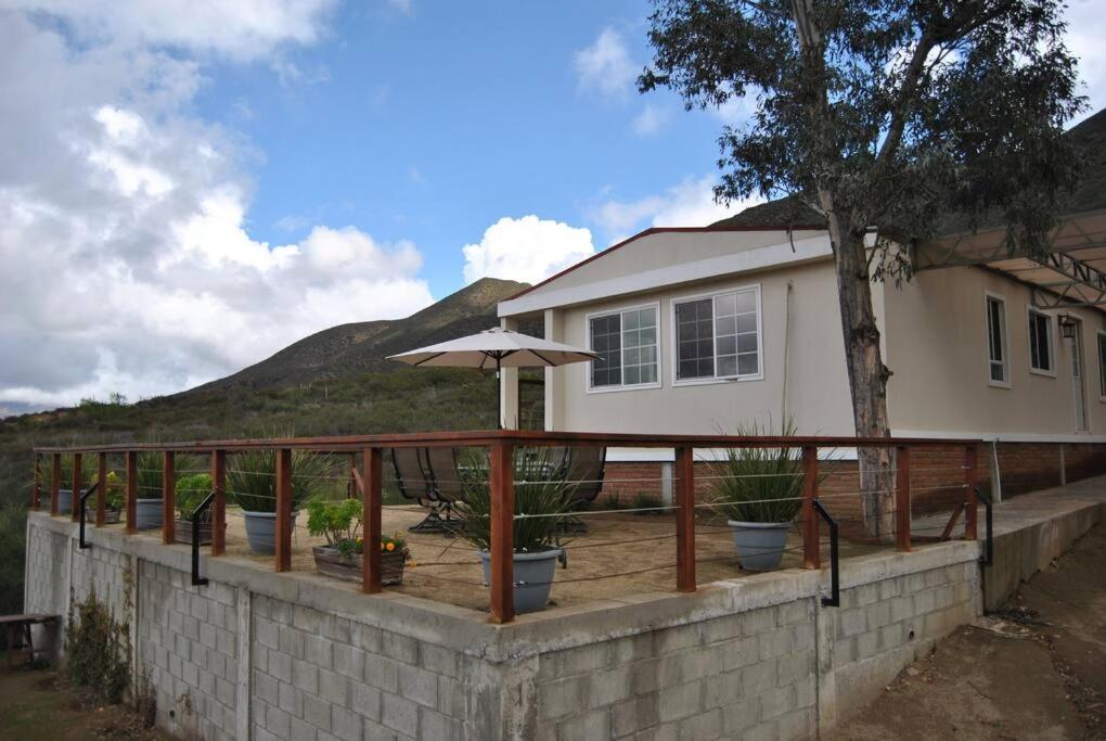 Villa de JuárezCasa de campo en ruta del vino的房屋上带盆栽和雨伞的甲板