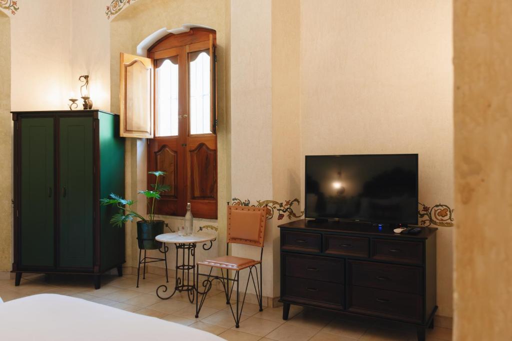 瓦哈卡市Los Pilares Hotel的一间卧室配有电视和桌椅