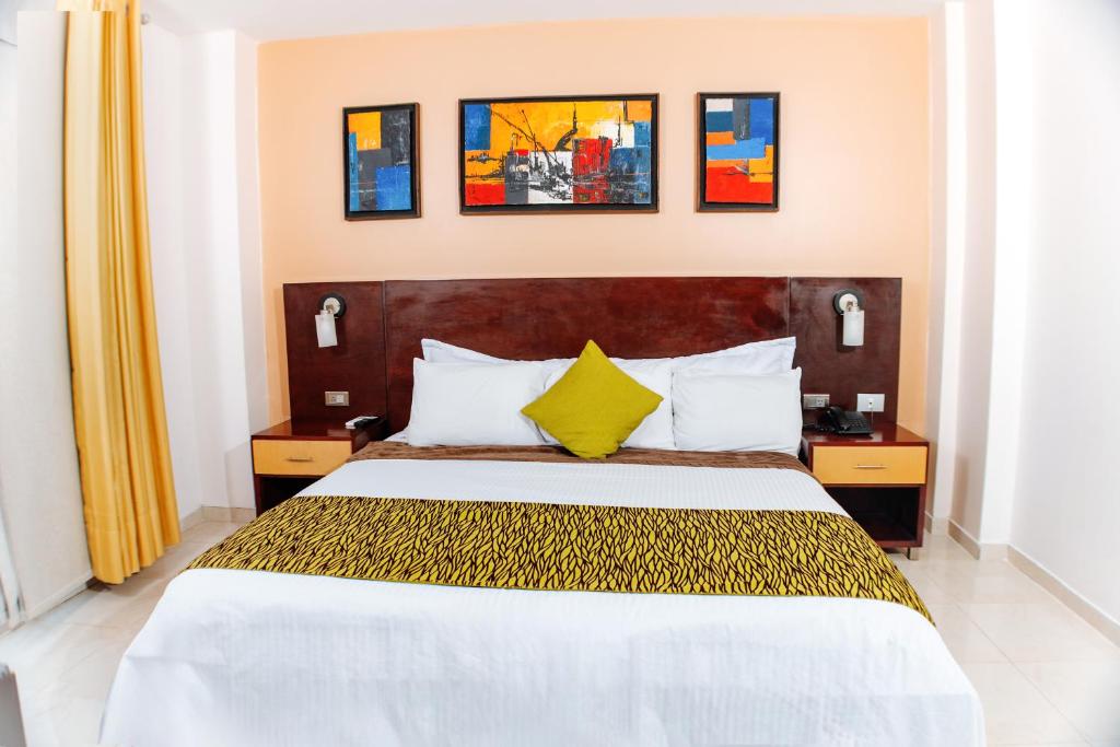 库库塔Hotel Luxor Cúcuta的酒店客房配有一张带黄色枕头的大床