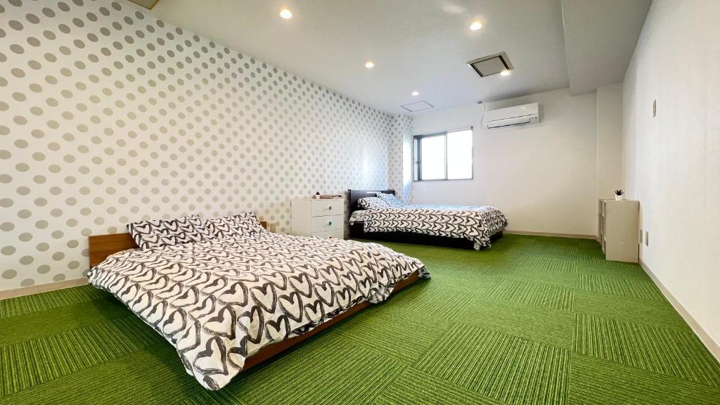 大阪心斎橋USJ155m2 Party OK JR駅徒歩1分的一间卧室配有两张床,铺有绿色地毯