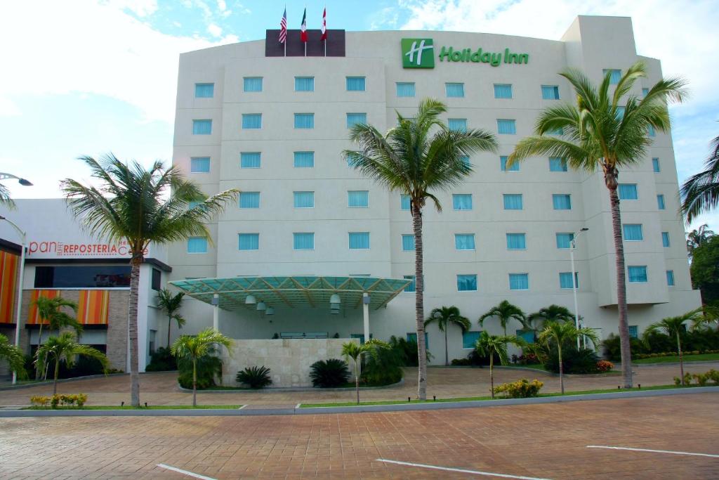 阿卡普尔科阿卡普尔科拉岛假日酒店的一座白色的大建筑,前面有棕榈树
