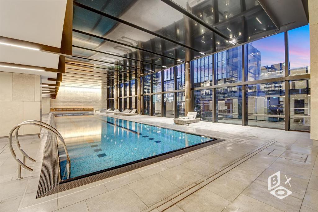 墨尔本Rest SkyHigh Melbourne Qtr Collection的一座大型游泳池,位于一座带大窗户的建筑内