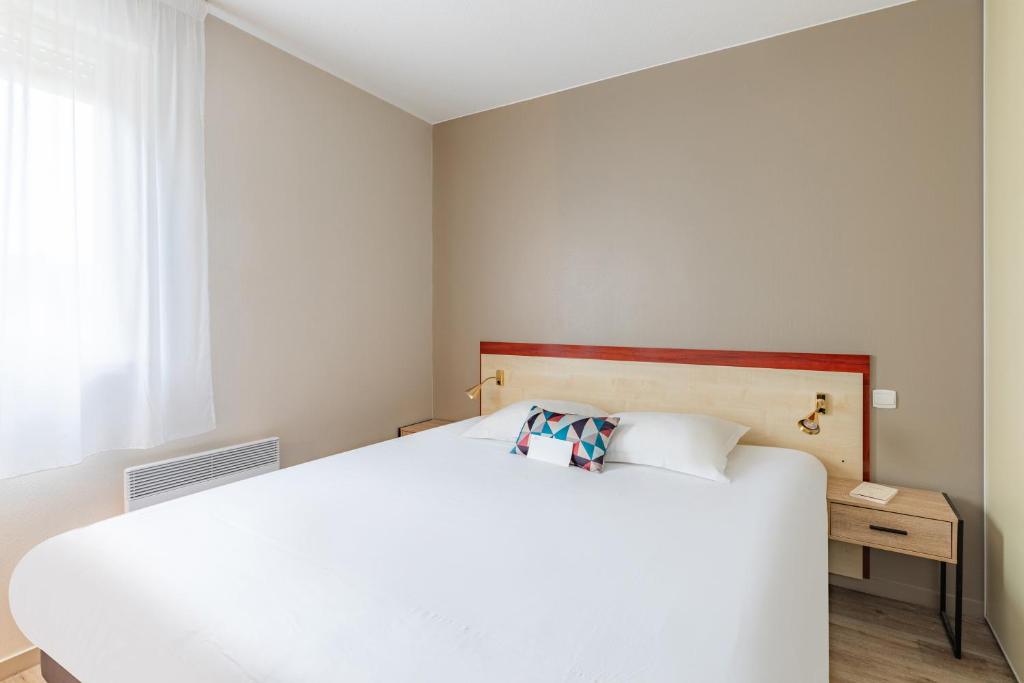 里摩日Appart'City Classic Limoges的卧室配有白色的床和窗户。
