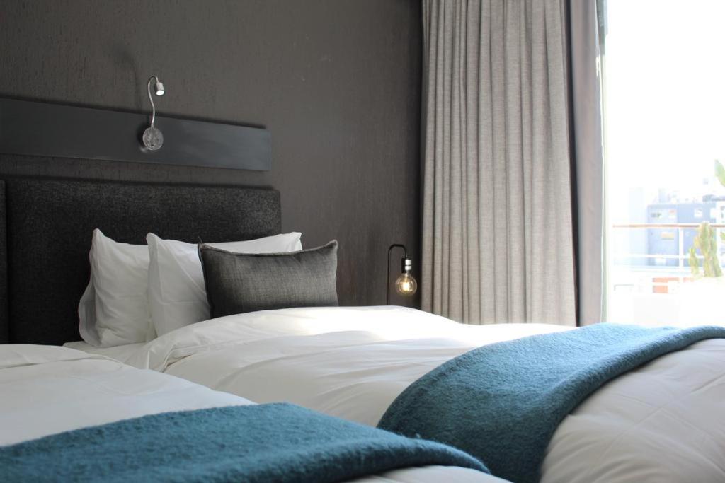 开普敦大西洋事理精品酒店的一间卧室设有两张白色的床和窗户