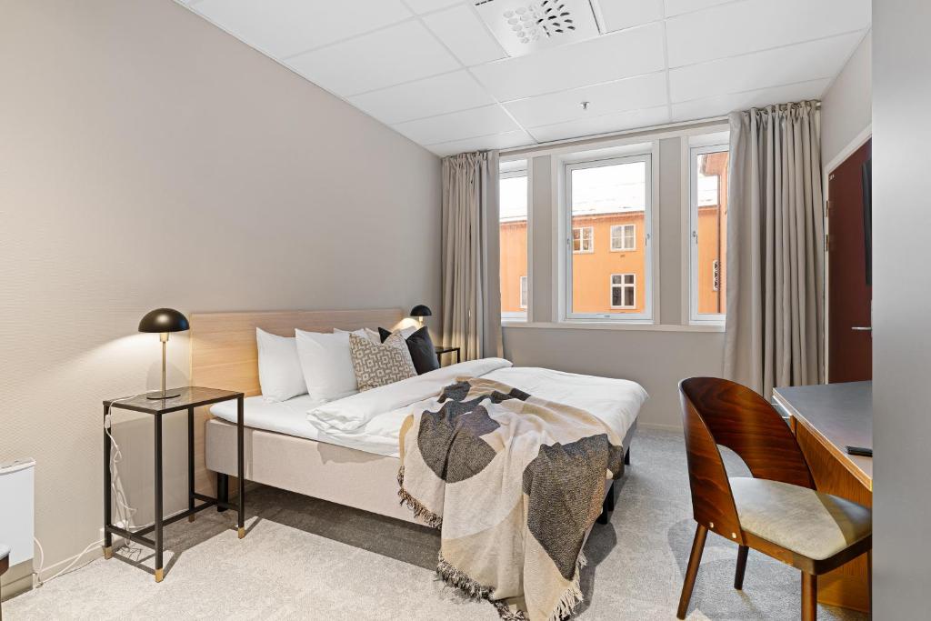 特罗姆瑟Enter St Elisabeth Hotel & Spa的一间卧室配有一张床、一张书桌和一个窗户。