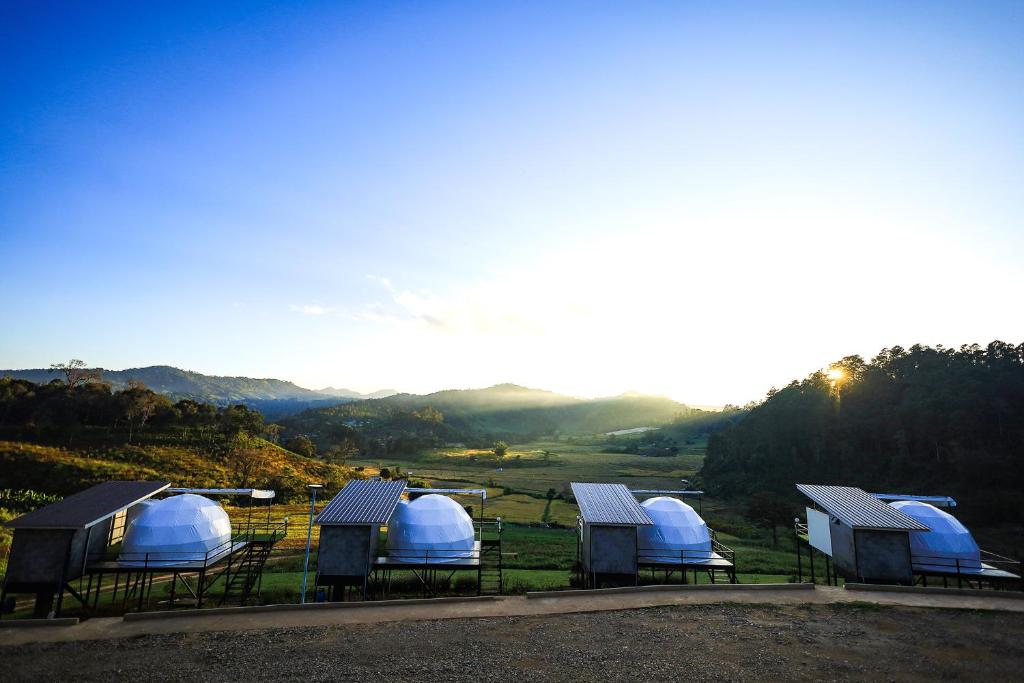 Ban Na Pa Paekสวนไร่รุ่งอรุณ的一组圆顶,位于一个有山背景的田野中