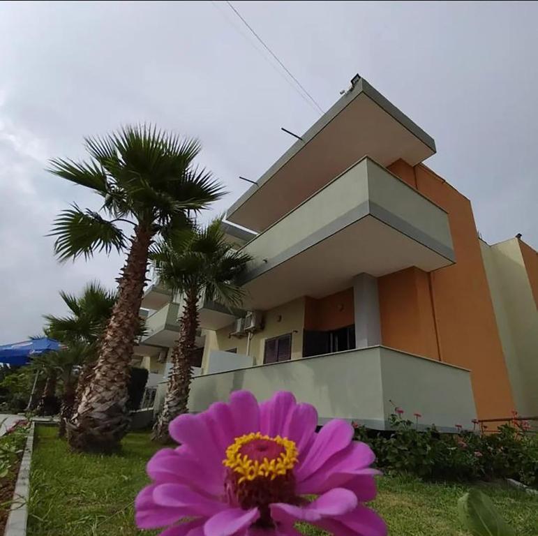 卡瓦亚Hotel Jaho的棕榈树屋前的粉红色花