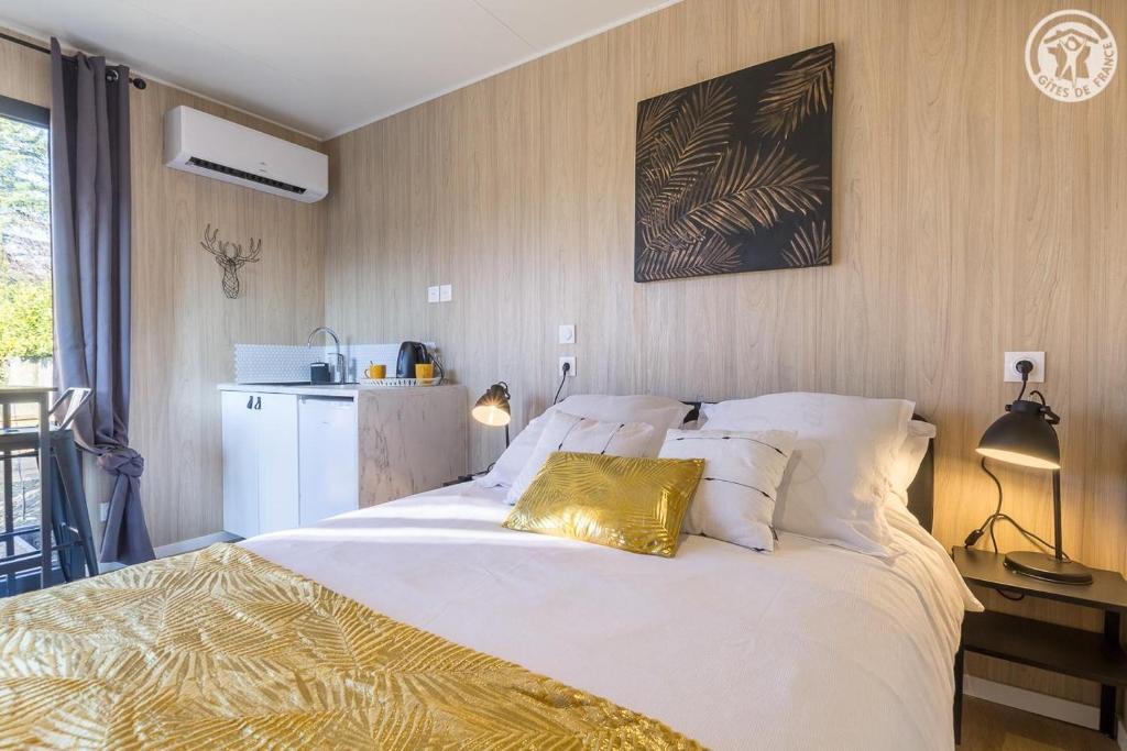 艾克斯莱班La cabane du pecheur的卧室配有一张带金色枕头的大型白色床