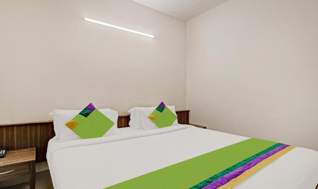 班加罗尔Hotel Prime Pavilion-MG ROAD的卧室配有一张带彩色枕头的大型白色床。