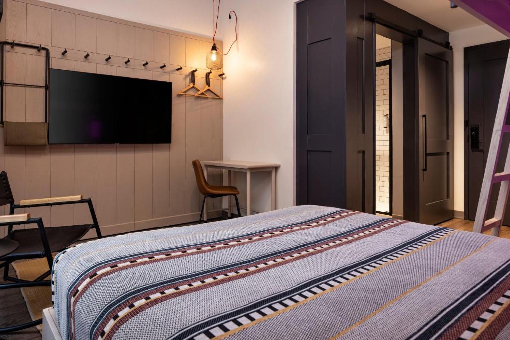 奥马哈Moxy Omaha Downtown的一间卧室配有一张床和一台平面电视