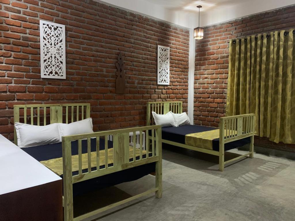 MadamSky 14 Resort Yala的一间设有两张婴儿床和砖墙的房间