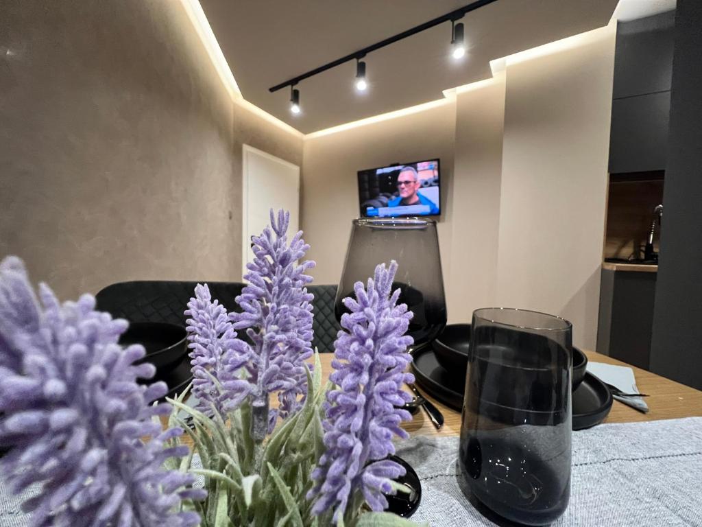 LovechApartament Varosha LUXURY的一张带紫色花的桌子和一台电视机