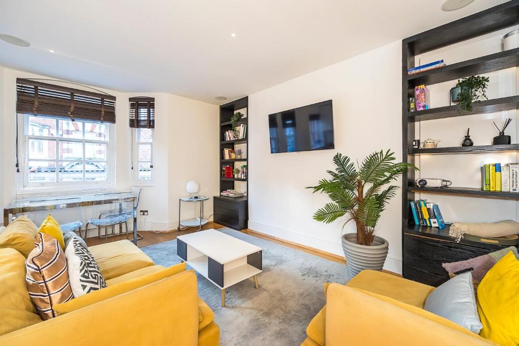伦敦Lux Duplex near Oxford St的客厅配有两张黄色的沙发和一张桌子