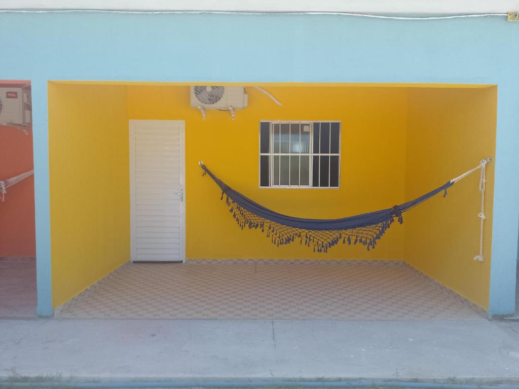 佩罗巴Casa morada da praia 5的一间设有黄色墙壁的客房,墙上配有吊床