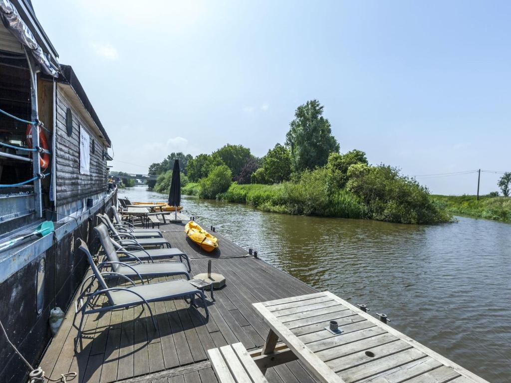 Drie GrachtenCozy Boat in Merkem near Lake的坐在河边码头上的一组椅子