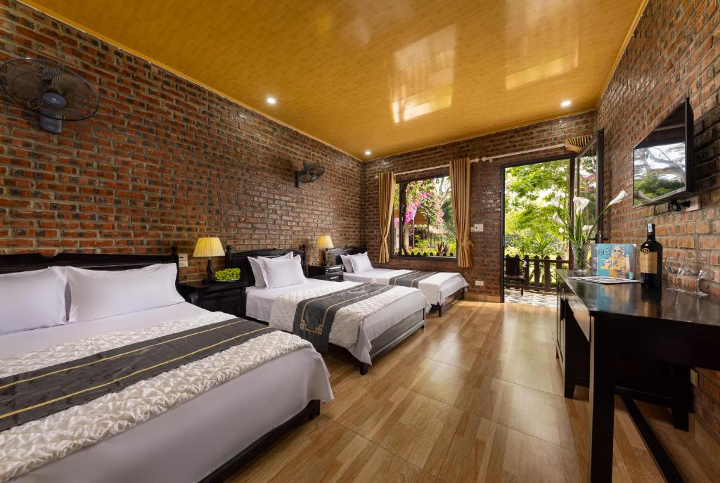 吉婆岛Green Homestay的一间卧室设有三张床和砖墙