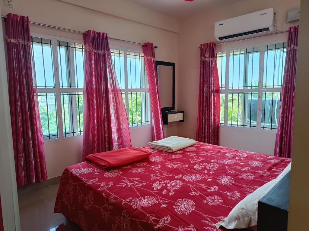 古鲁瓦尤尔2 BHK Furnished Flat - 200 m to Guruvayur Temple - For FAMILIES ONLY的一间卧室配有一张带红色床单和窗户的床。