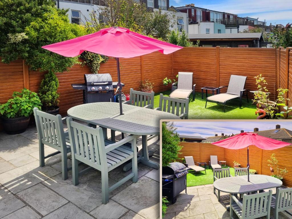 布莱顿霍夫Sunny Queens Park Home - Garden & Private Parking的天井配有桌椅和粉红色雨伞。