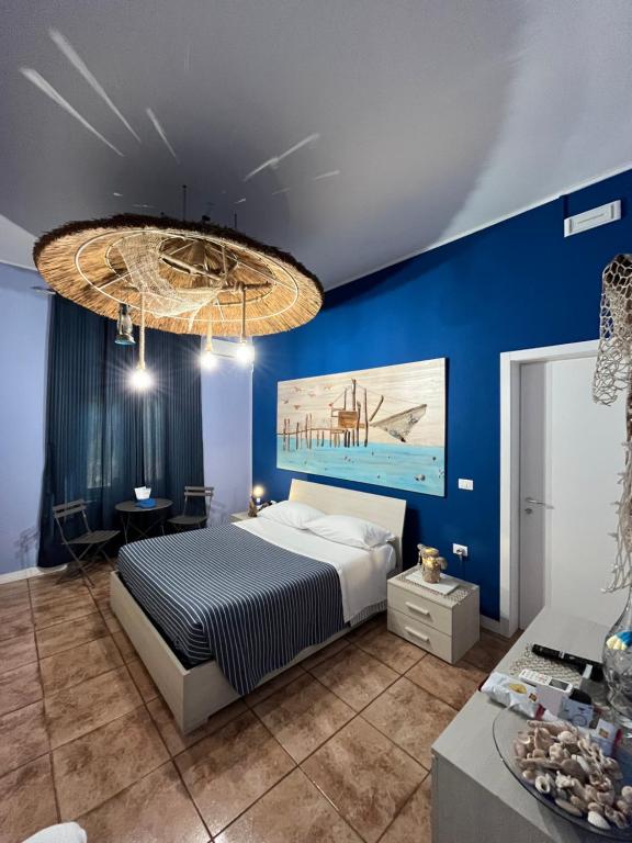 佩斯卡拉Marini Bed&Breakfast的一间拥有蓝色墙壁的卧室、一张床和一个吊灯