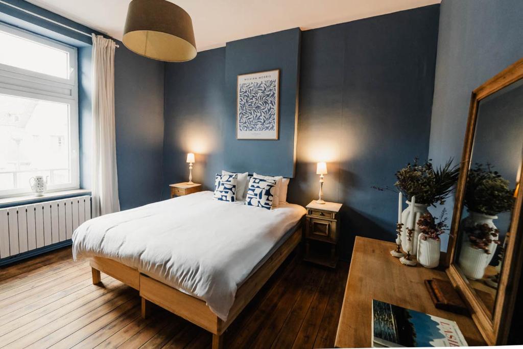 罗什福尔Maison Comtale的一间卧室配有一张带蓝色墙壁和镜子的床