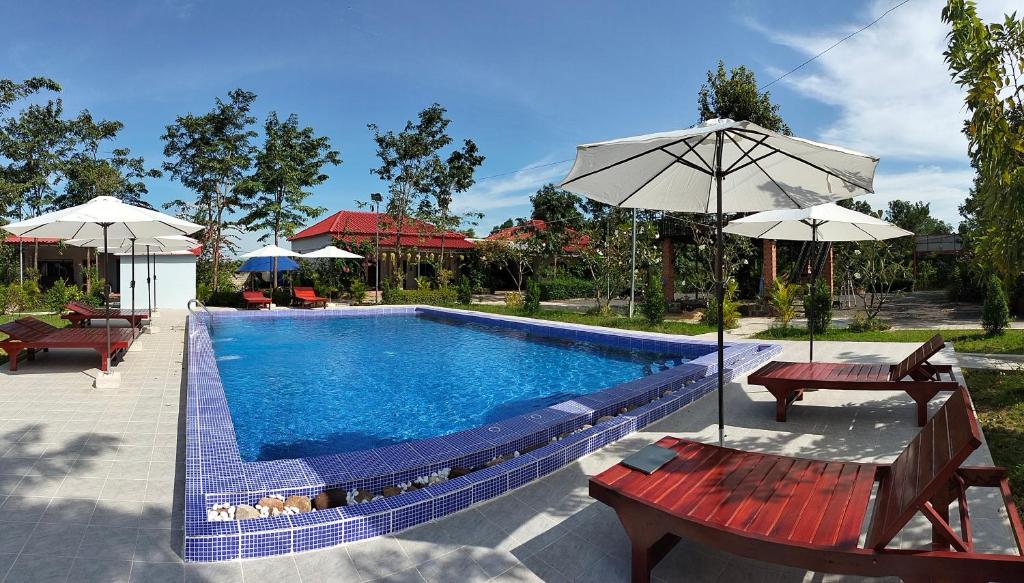 贡布Kampot Nature Villa Resort的一个带2个长椅和遮阳伞的游泳池