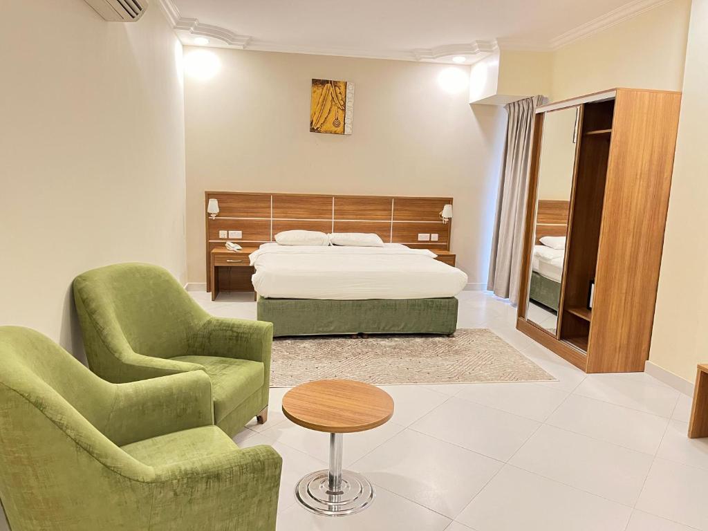 马斯喀特Muscat Hills Hotel的一间卧室配有一张床、两把椅子和一张桌子