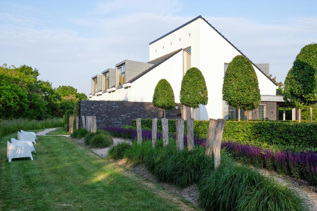 佐特兰德Villa Zoutelande的白色的房子,花园内种有紫色花卉
