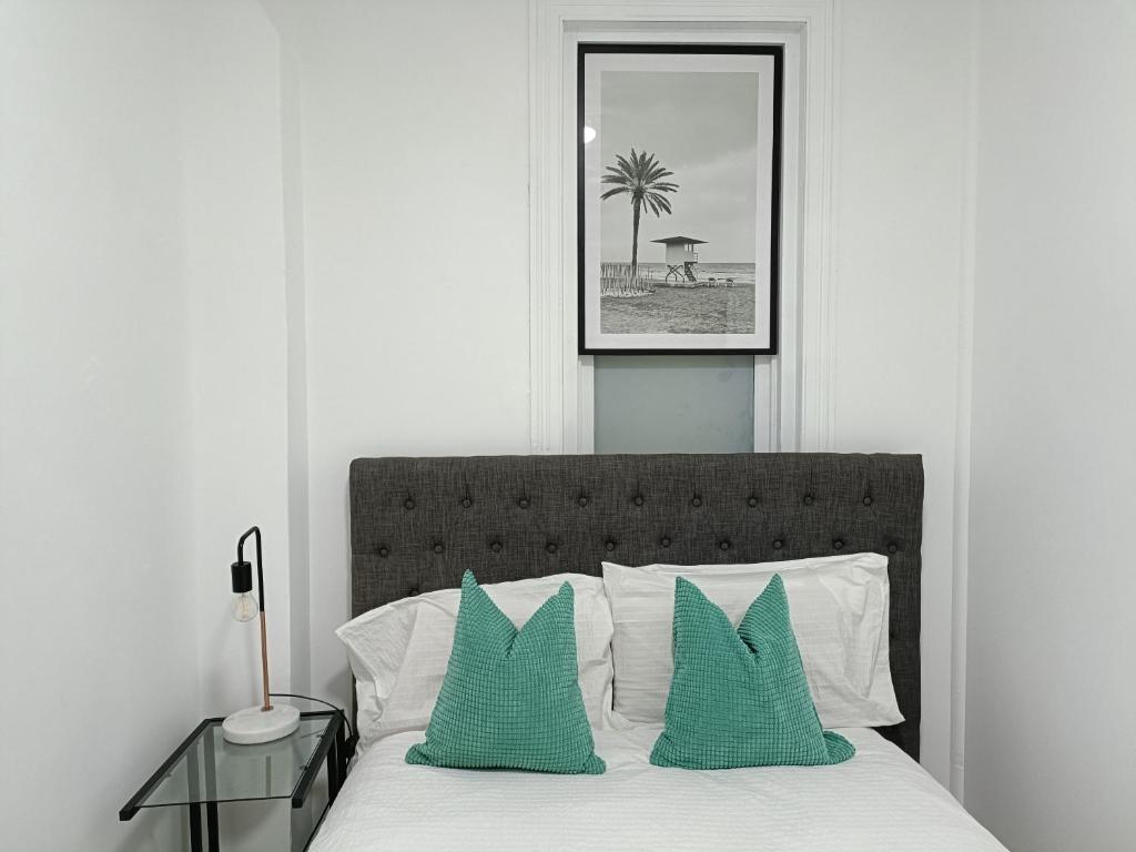 悉尼Lovely Room 1Min Walk to Station with 55Inch TV的一间卧室配有一张带两个绿色枕头的床