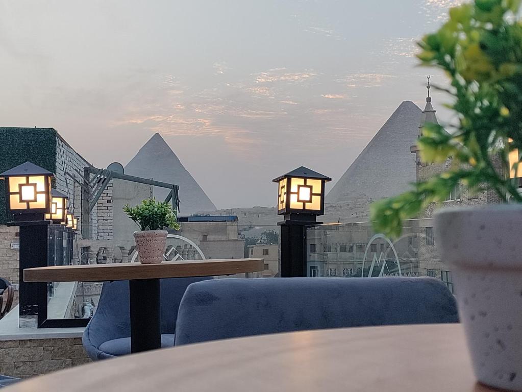 开罗Locanda Pyramids Hotel的一个带金字塔的阳台的桌椅
