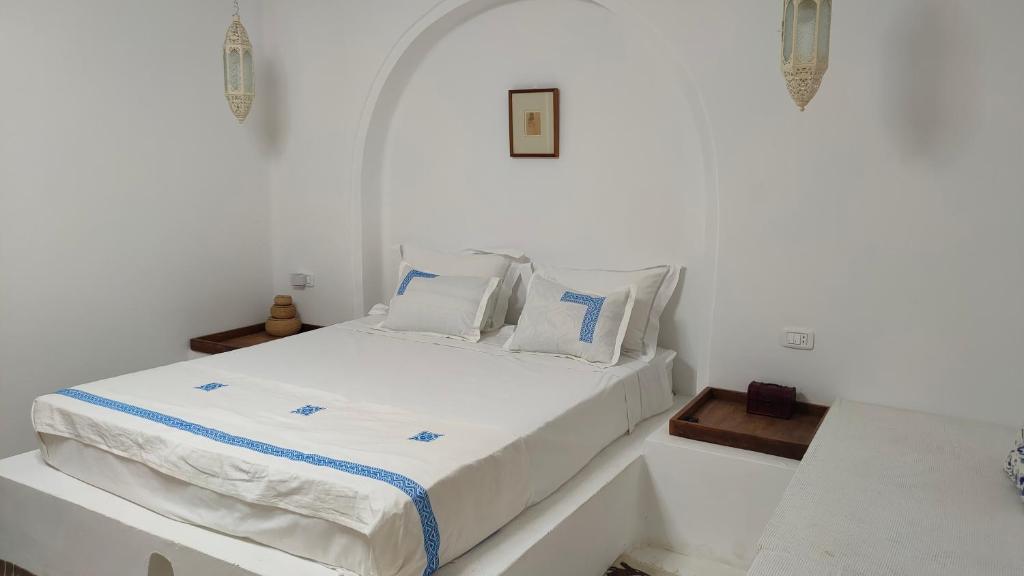 Maison d’hôte, Djerba的白色卧室配有带白色床单和枕头的床