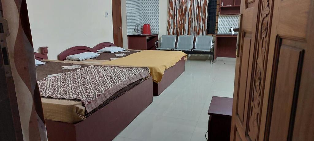 古鲁瓦尤尔Guruvayur Adithya的两张位于带椅子的房间的床铺
