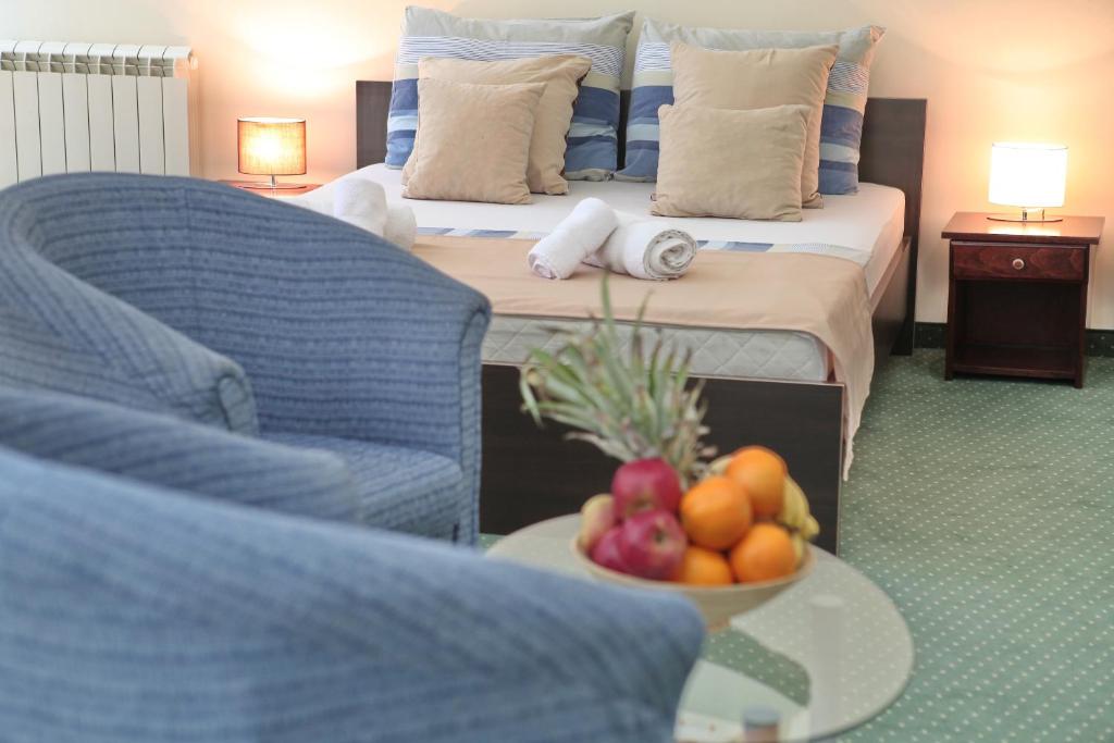 贝尔格莱德快乐星俱乐部酒店的一间房间,桌子上放着一张床和一碗水果