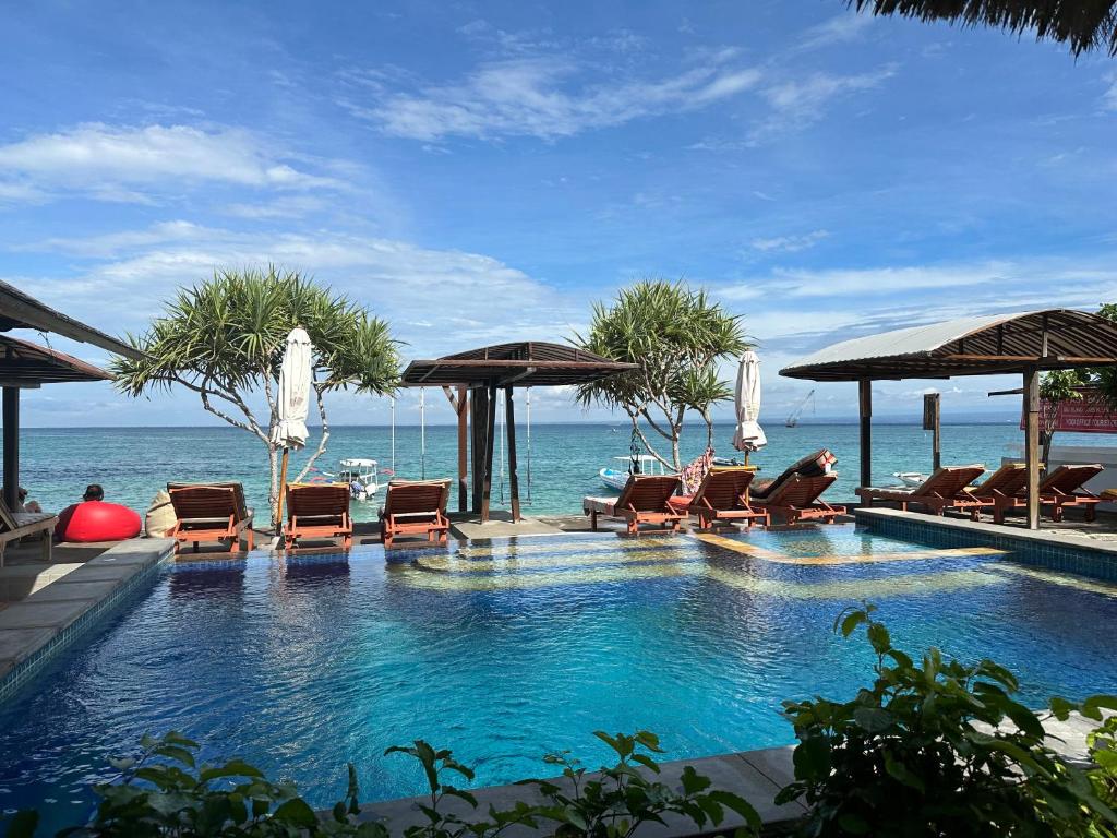 蓝梦岛Ketut Losmen Bungalows Lembongan的毗邻大海的带椅子和遮阳伞的游泳池