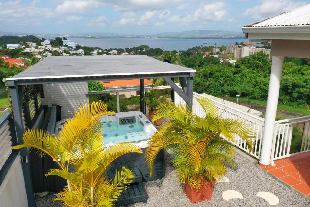 莱特鲁瓦西莱Villa Sweet Caraïbes, vue mer, jacuzzi的阳台位于房子内,拥有游泳池和棕榈树