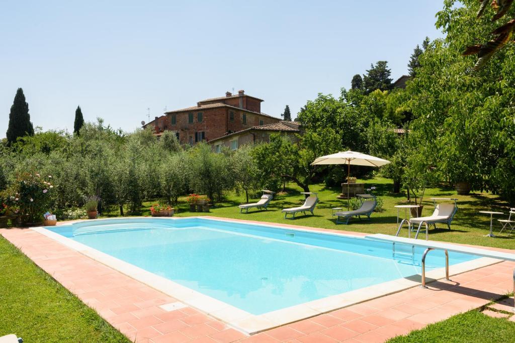 贝托勒Villa Vignacce - Boutique Country Resort的庭院内的游泳池配有椅子和遮阳伞