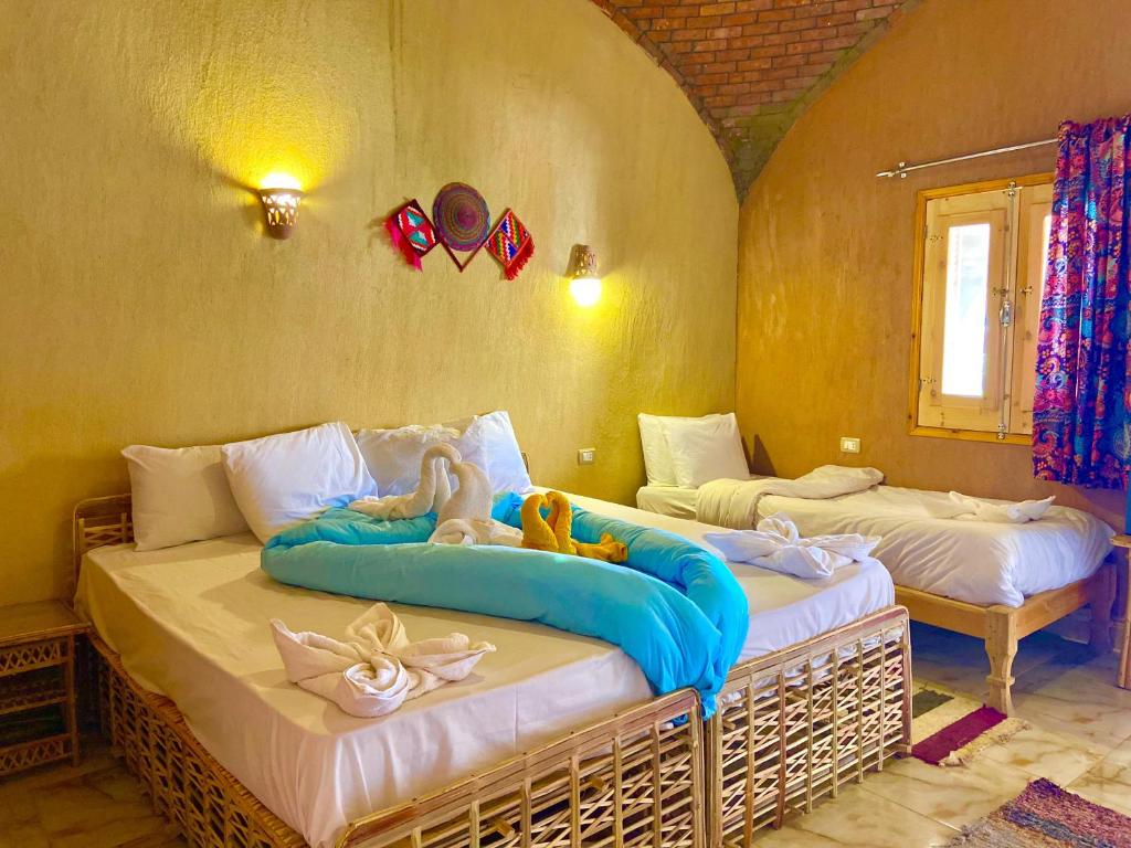 阿布辛贝Kabara Nubian House的一间卧室设有两张床,里面饲养着动物。