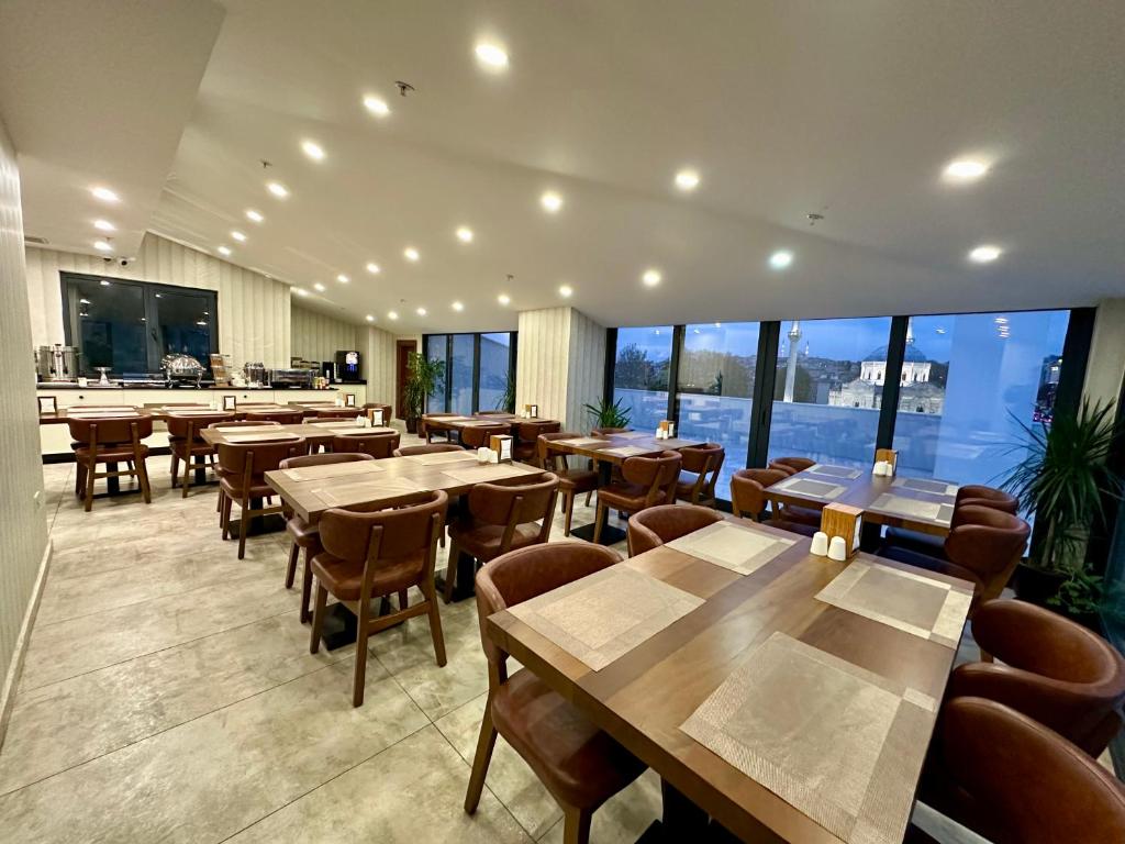 伊斯坦布尔Istanbul Midpoint Hotel的餐厅设有桌椅和大窗户。
