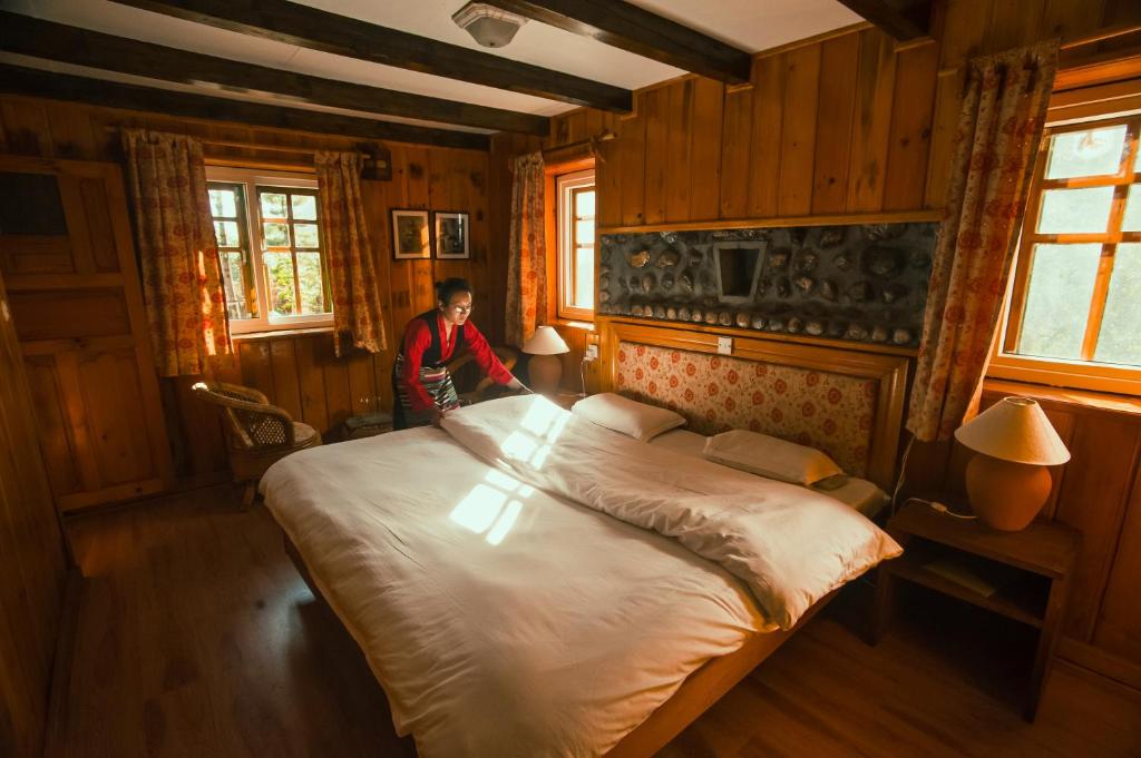 PhakdingMountain Lodges of Nepal - Phakding的站在卧室里,有一张大床的人