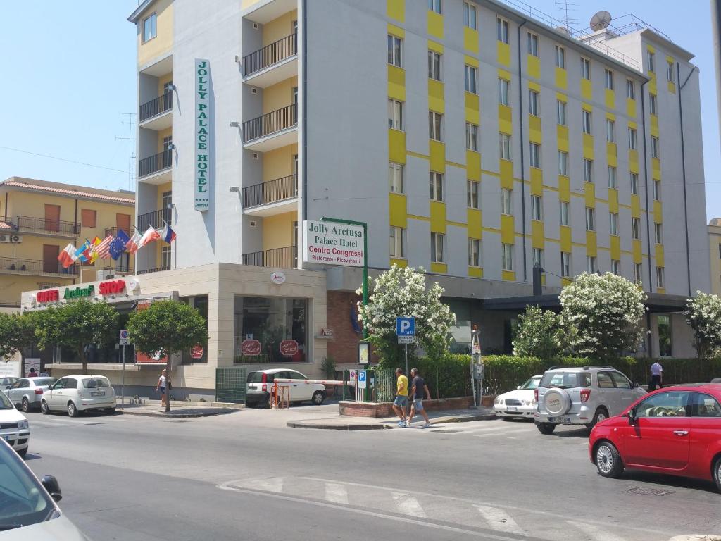 锡拉库扎Aretusa Palace Hotel的一条城市街道,汽车停在大楼前
