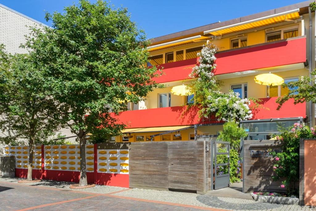 诺德奈neyland apartments Norderney的一座红色和黄色的建筑,有栅栏和树木